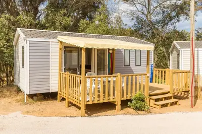 a small house with a porch and a deck at Camping Corsica Paradise in Calcatoggio