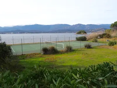 a tennis court next to a body of water at Villa 8 au Village Marin in Porto-Vecchio