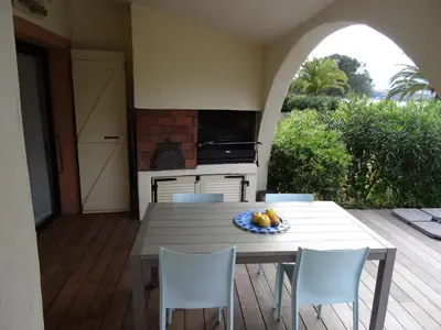 a table and chairs on a deck with a kitchen at Villa 8 au Village Marin in Porto-Vecchio