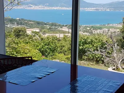a room with a table and a view of the ocean at A Mandria in Porticcio
