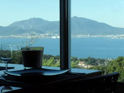 a table with a glass of wine and a view of the water at A Mandria in Porticcio