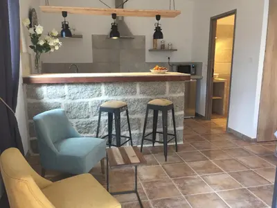 a kitchen with a bar with two chairs and a table at Maredda 1 in Sartène