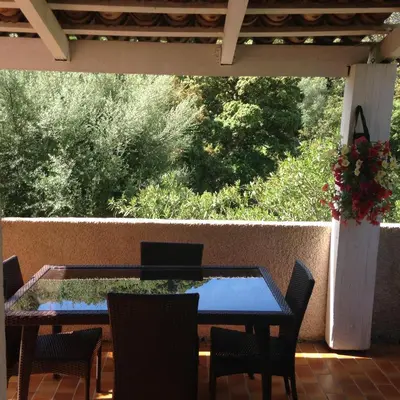 a table and chairs on a patio with a view of trees at Maredda 1 in Sartène
