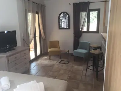 a bedroom with a bed and two chairs and a tv at Maredda 1 in Sartène