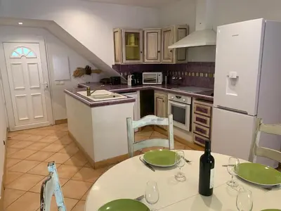 a kitchen with a table and a white refrigerator at Villa Pampasgiolu in Tizzano