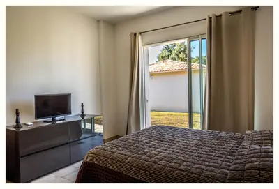a bedroom with a bed and a tv and a sliding glass door at Villa 4 étoiles Sole di Corsica in Cauro