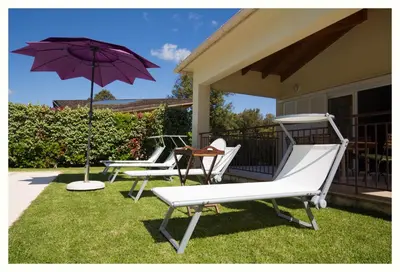 a couple of chairs and an umbrella on a porch at Villa 4 étoiles Sole di Corsica in Cauro