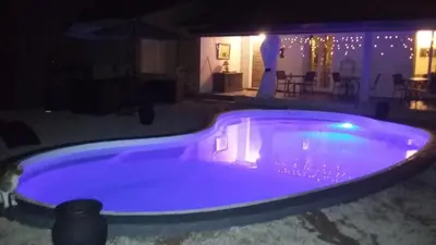 a large blue swimming pool in a yard at night at A Casa di Mariano in Alata