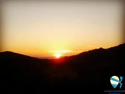 a sunset with the sun setting over the mountains at A Casa di Mariano in Alata