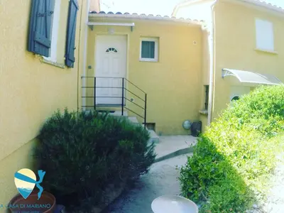 a yellow house with a staircase leading to a white door at A Casa di Mariano in Alata