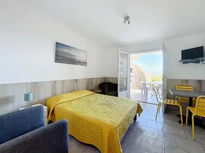 a bedroom with a bed with a yellow bedspread at Résidence Les Pavillons du Belvédère in Porto-Vecchio