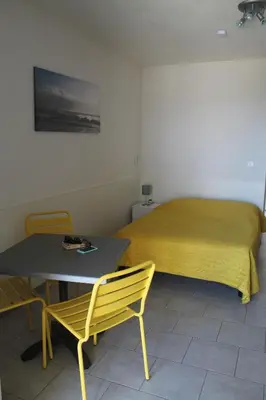 a bedroom with a bed and a table and a yellow bedspread at Résidence Les Pavillons du Belvédère in Porto-Vecchio