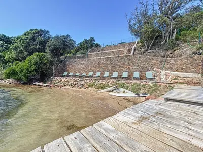 a view of a beach with a surfboard on the sand at Résidence Les Pavillons du Belvédère in Porto-Vecchio