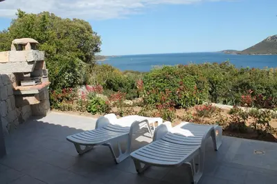 a patio with two chairs and a view of the water at Résidence Les Pavillons du Belvédère in Porto-Vecchio