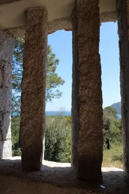 a window in a stone building with trees in the background at Résidence Les Pavillons du Belvédère in Porto-Vecchio