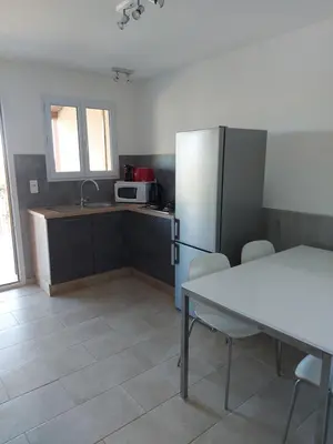 a kitchen with a white table and a refrigerator at Résidence Les Pavillons du Belvédère in Porto-Vecchio