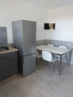 a kitchen with a refrigerator and a table with chairs at Résidence Les Pavillons du Belvédère in Porto-Vecchio