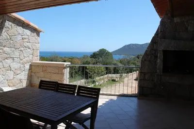 a black table and chair on a balcony with a view at Résidence Les Pavillons du Belvédère in Porto-Vecchio