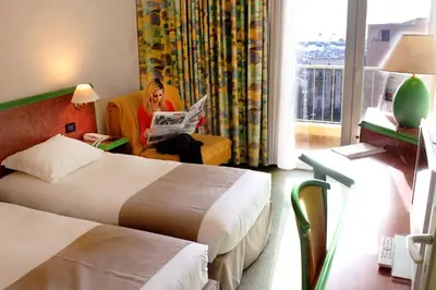 a woman sitting in a chair reading a newspaper in a hotel room at Castel Vecchio in Ajaccio