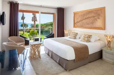 a hotel room with a bed and a large window at Hotel Le Ruesco in Olmeto
