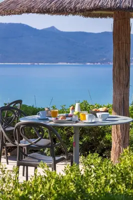 a table with food on it with a view of the ocean at Hotel Le Ruesco in Olmeto