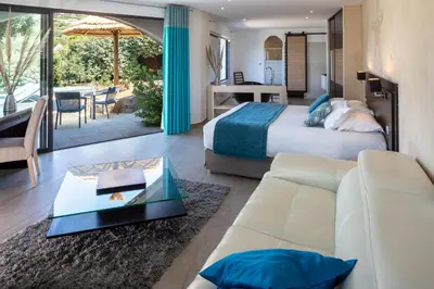 a hotel room with a bed and a living room at Hotel Le Ruesco in Olmeto