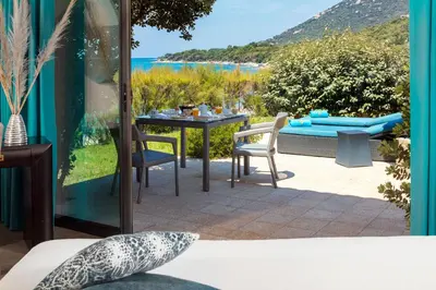 a patio with a table and chairs and a view of the ocean at Hotel Le Ruesco in Olmeto