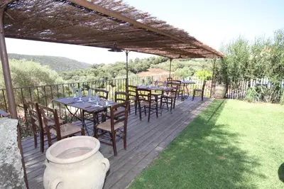 a wooden deck with tables and chairs under a pergola at Auberge U Sirenu in Sartène