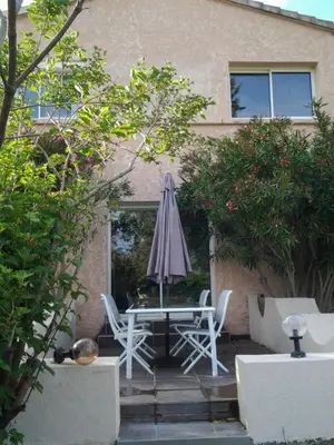 a patio with a table with an umbrella and chairs at Villa de charme avec piscine in Ghisonaccia