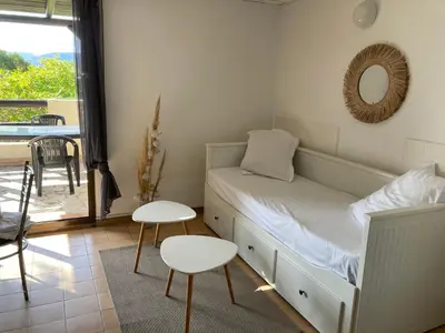 a bedroom with a bed and two tables and a balcony at Mini-villa Vista bella in Porto-Vecchio