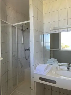 a bathroom with a shower and a sink and a mirror at Le Village des Isles in Taglio-Isolaccio