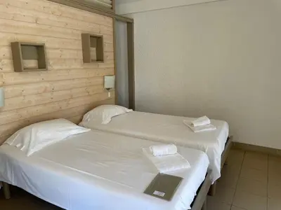two beds in a room with white sheets and towels at Le Village des Isles in Taglio-Isolaccio