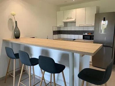 a kitchen with a counter with four blue bar stools at Cala Rossa Appart in Porto-Vecchio