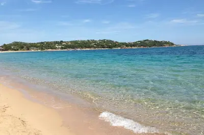 a beach with blue water and trees in the background at Cala Rossa Appart in Porto-Vecchio