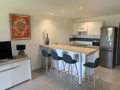 a kitchen with a bar with stools and a refrigerator at Cala Rossa Appart in Porto-Vecchio