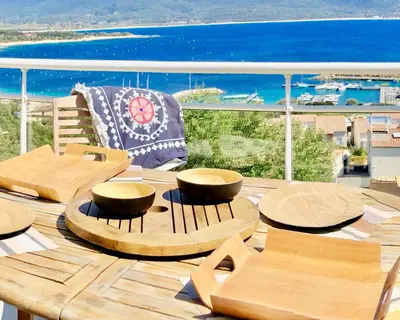 a deck with tables and chairs and the ocean at Les Villas MarInCelu in Porto Pollo