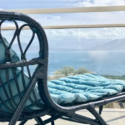 a wicker chair with a mattress in front of a window at Les Villas MarInCelu in Porto Pollo