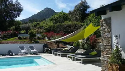 a patio with a hammock and a swimming pool at A Sulana Chambre d'hôtes in Valle-di-Campoloro