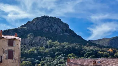 a mountain in the distance with a building and trees at locations calenzana in Calenzana