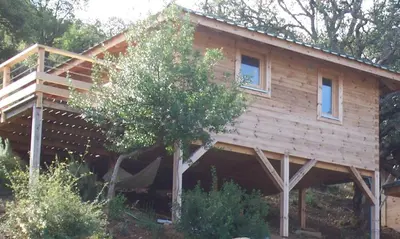a log cabin with a porch and a tree at Albaria Lodge in Saint-Florent