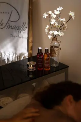 a person laying on a couch with a table with a vase of flowers at Le Pinarello in Sainte-Lucie de Porto-Vecchio