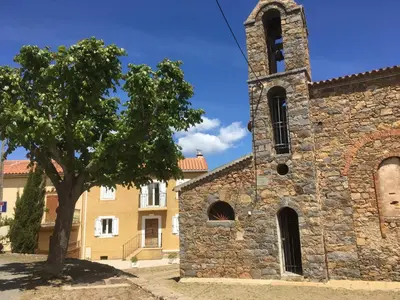 an old stone church with a tree in front of it at indé no in Sari Solenzara