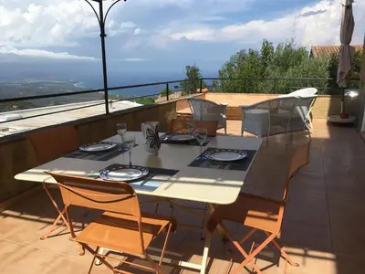 a dining table and chairs on a balcony with a view at indé no in Sari Solenzara