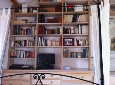 a book shelf with a computer on a desk at indé no in Sari Solenzara