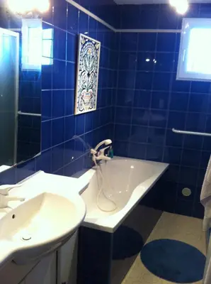 a blue tiled bathroom with a tub and a sink at indé no in Sari Solenzara