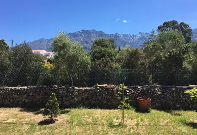 a stone wall with trees and mountains in the background at Studio Pinzali Avec Mezzanine in Calenzana