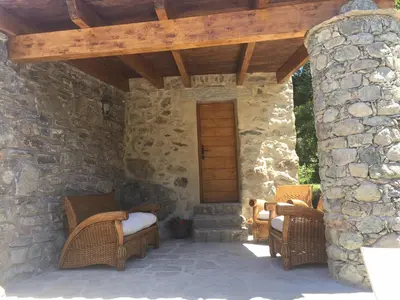 a patio with wicker chairs and a stone wall at U Fragnu in Omessa
