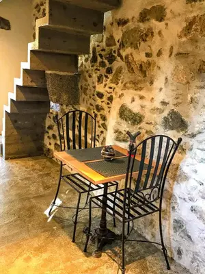 a table and two chairs in front of a stone wall at U Fragnu in Omessa