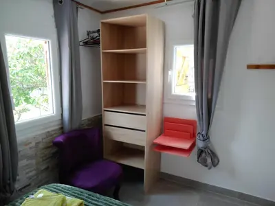 a bedroom with a closet with a red stool and a chair at Maison Lisa Maria in Ponte-Leccia