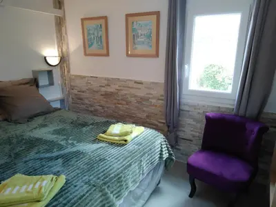 a bedroom with a bed and a purple chair at Maison Lisa Maria in Ponte-Leccia